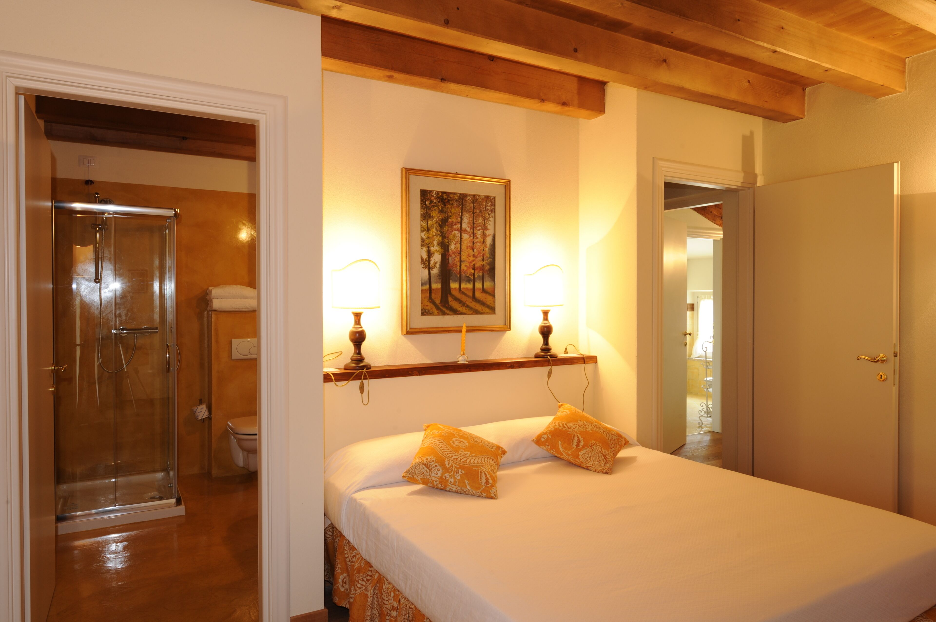 Una camera da letto con un letto, due lampade sui comodini, un quadro appeso al muro e una trave in legno al soffitto.