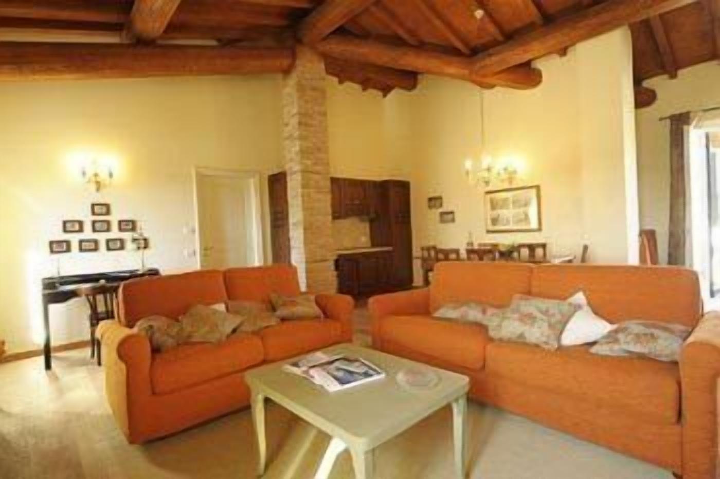 Una sala de estar con dos sofás naranjas, una mesita y un pilar de piedra.
