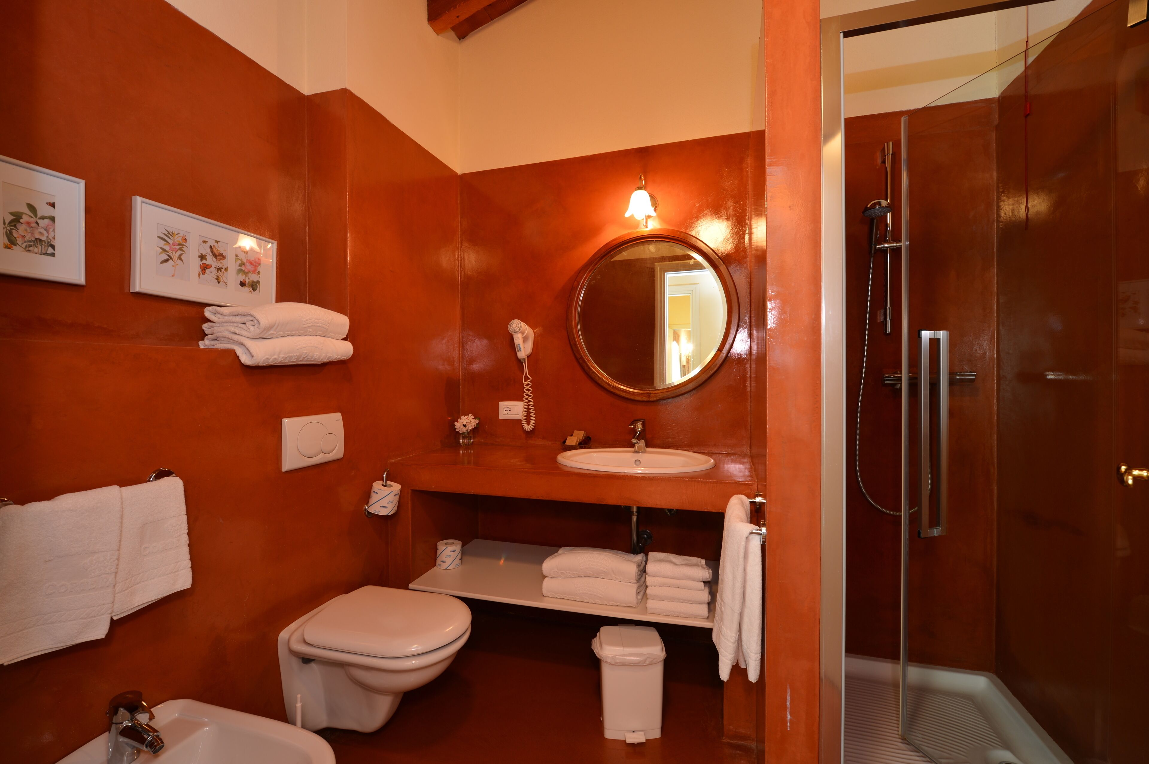 Ein Badezimmer mit Toilette, Waschbecken und Dusche. Handtücher und ein Spiegel sind vorhanden.