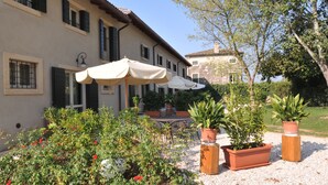 A building with a patio area, outdoor seating, and potted plants. - Relais Corte Paradiso (Peschiera del Garda)