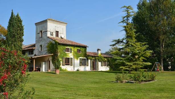 A large, white building with a tower, surrounded by a well-maintained lawn and trees. - Relais Corte Paradiso (Peschiera del Garda)