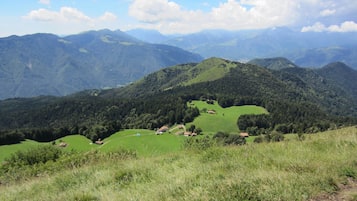 Panoramica di un paesaggio montuoso con valli verdi e case sparse.