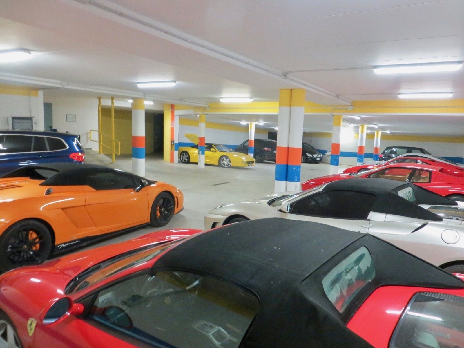 Un estacionamiento con varios niveles y varios coches deportivos aparcados.