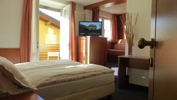 A hotel room with a bed, a desk, a television, and a view of the outside.
