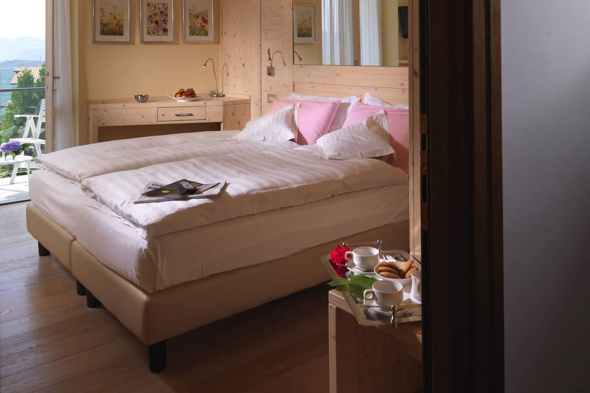 Un dormitorio con una cama grande, una mesita de noche con un desayuno servido sobre una bandeja, un espejo y vistas al exterior.