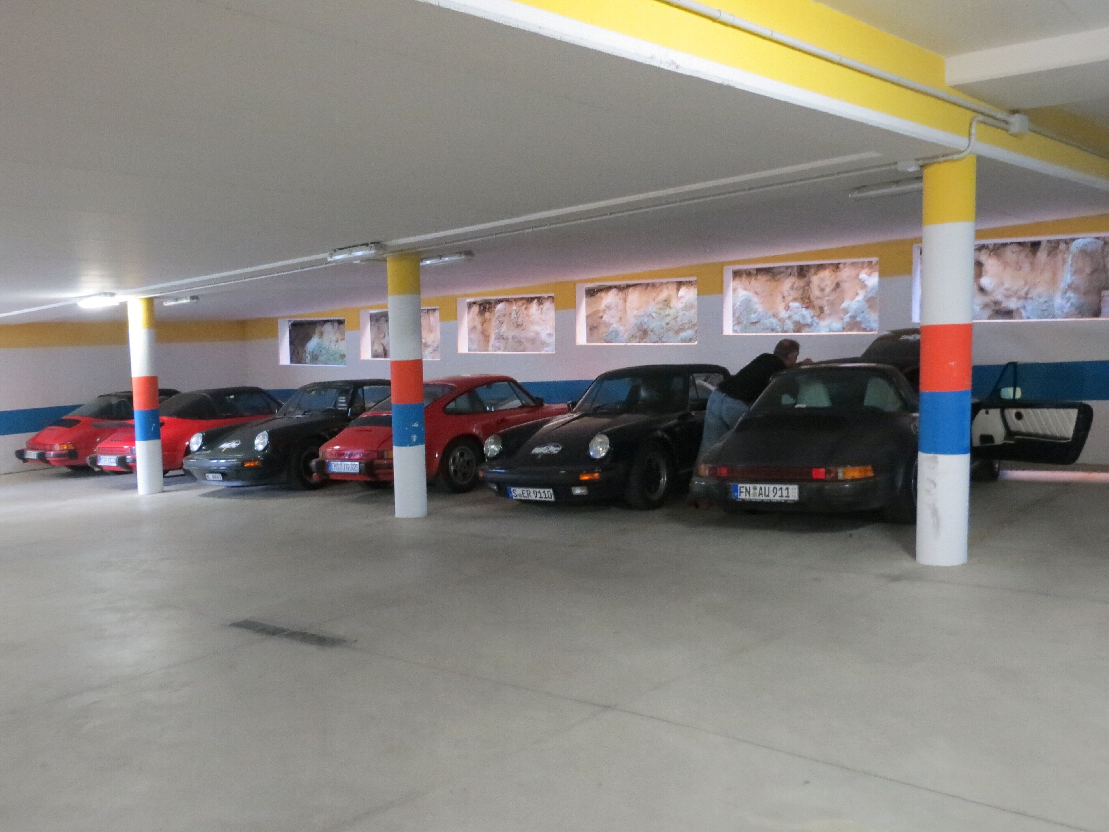 Eine Parkgarage mit mehreren Autos unter farbigen Säulen.