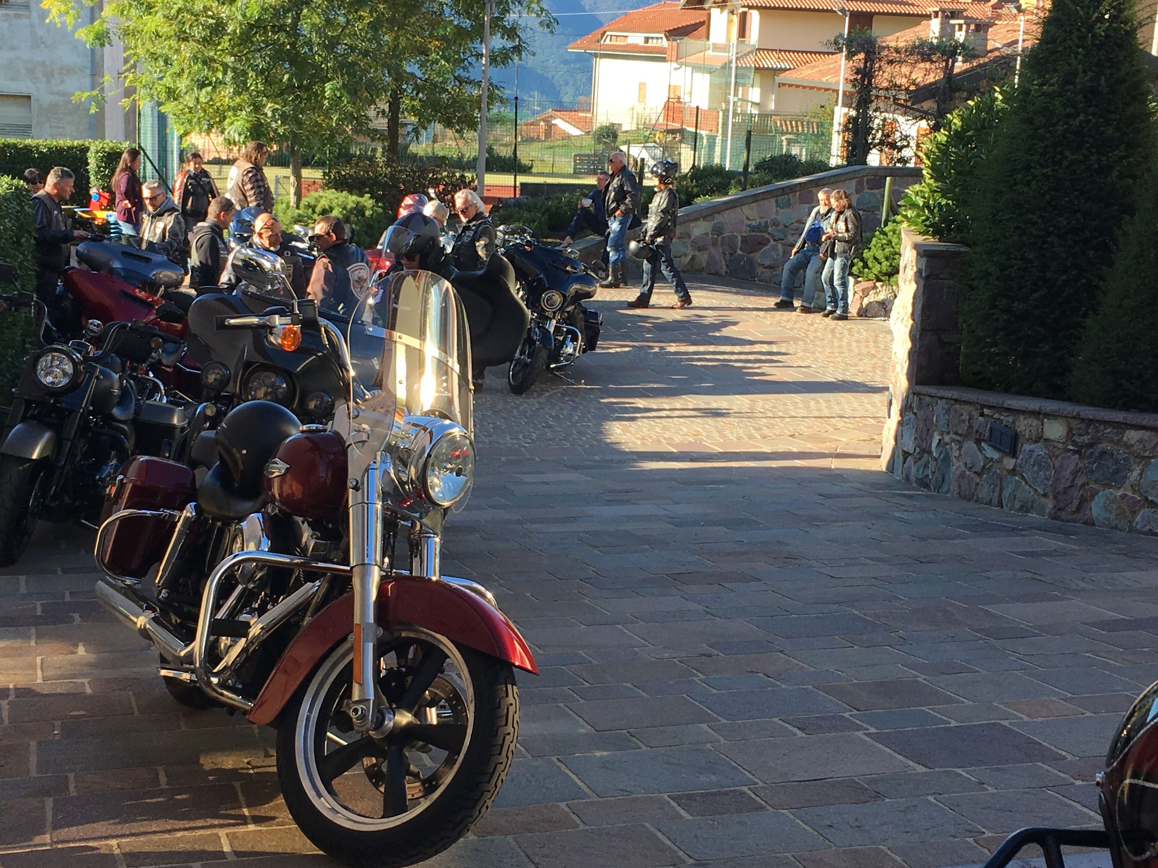 Ein gepflasterter Bereich mit abgestellten Motorrädern und einer Steinmauer.
