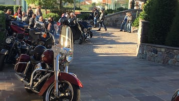 Ein gepflasterter Bereich mit abgestellten Motorrädern und einer Steinmauer.