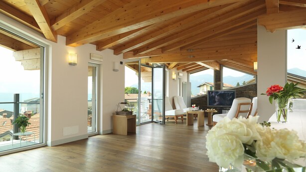 Un espacio habitable amplio con vigas de madera, un ventanal y vista al mar.