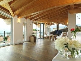 Un espacio habitable amplio con vigas de madera, un ventanal y vista al mar.