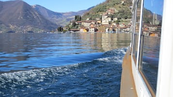 A lake with a boat, calm water, and a hillside with buildings.
