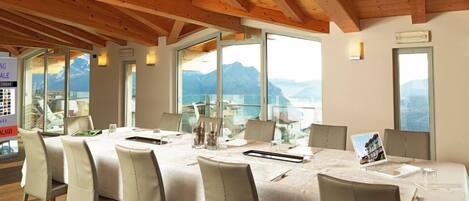 A conference room with a large table, chairs, and a view of mountains through large windows.