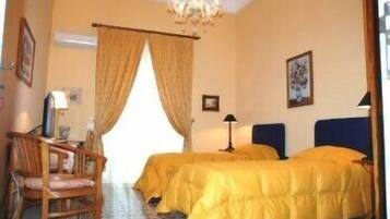 A hotel room with two beds, a desk, a chair, and a chandelier.