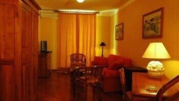 A room with a wooden cabinet, a sofa, a table with a lamp, and a chair.