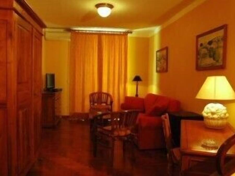 A room with a wooden cabinet, a sofa, a table with a lamp, and a chair.