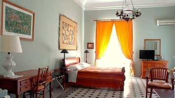Relax in a cozy space with a neatly made bed, wooden desk, and framed artworks.