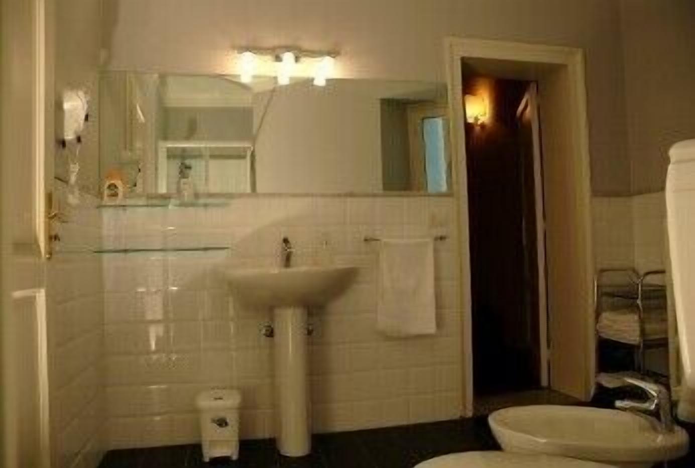 A bathroom with a white sink, a mirror, and a towel hanging on the wall.
