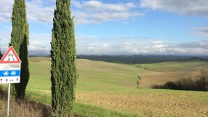 Un paysage rural caractérisé par des collines douces, un ciel dégagé et un panneau d’avertissement indiquant que la chaussée est glissante.