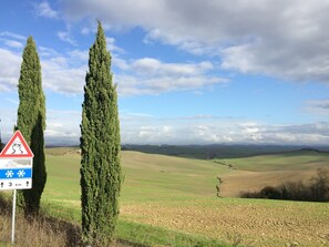 A rural landscape with rolling hills, a clear sky, and a warning sign indicating slippery roads ahead.