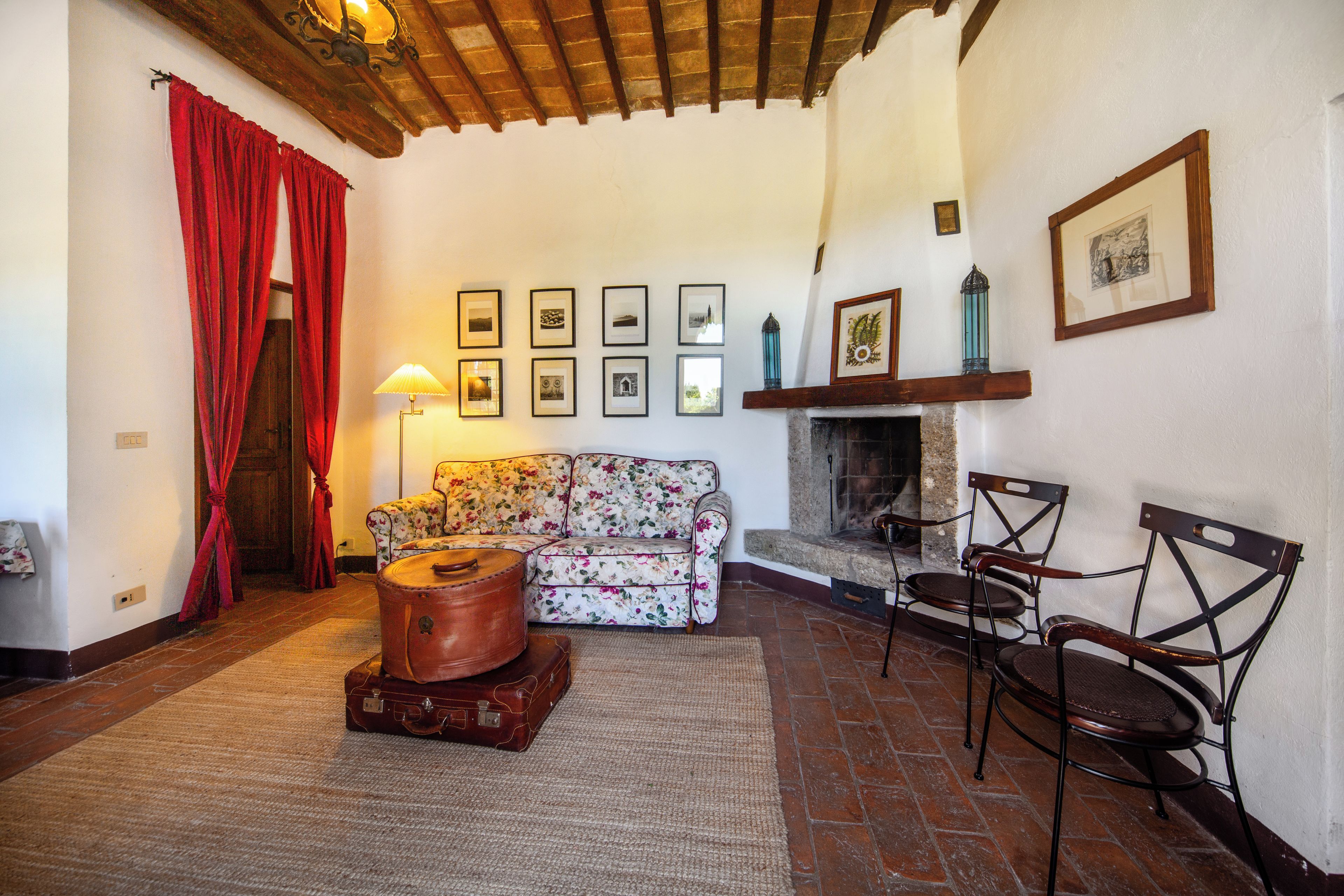 Una sala de estar acogedora con un sofá floral, una chimenea y una colección de cuadros en la pared.