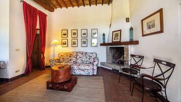 Una sala de estar acogedora con un sofá floral, una chimenea y una colección de cuadros en la pared.