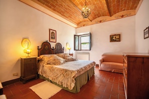 A bedroom with a bed, bedside tables, a radiator, a window, and a sofa.