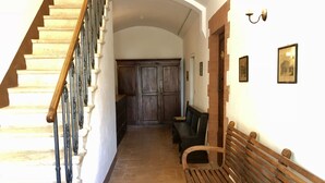 Un couloir avec un escalier en bois, un banc et une porte donnant sur une autre pièce.