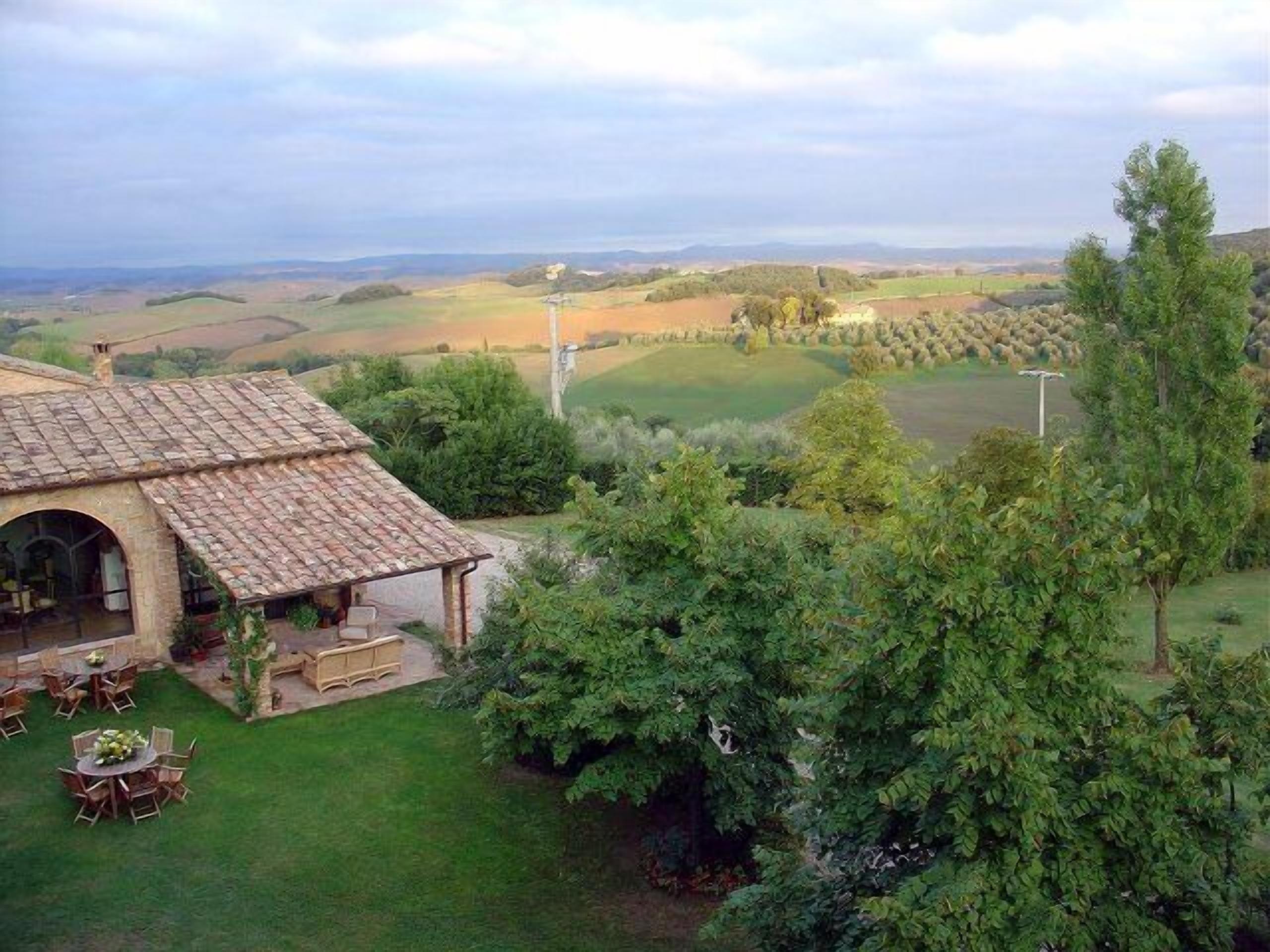 Una casa rústica con tejado de baldosas, un patio con mobiliario exterior y vistas a colinas ondulantes y un campo de golf.