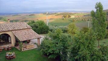 Una casa rústica con tejado de baldosas, un patio con mobiliario exterior y vistas a colinas ondulantes y un campo de golf.