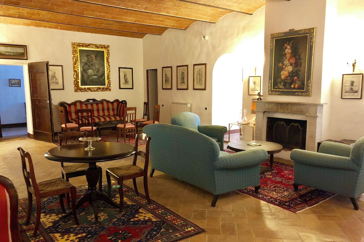 Una sala de estar tradicional con chimenea, un sofá, sillones y una mesa de comedor.
