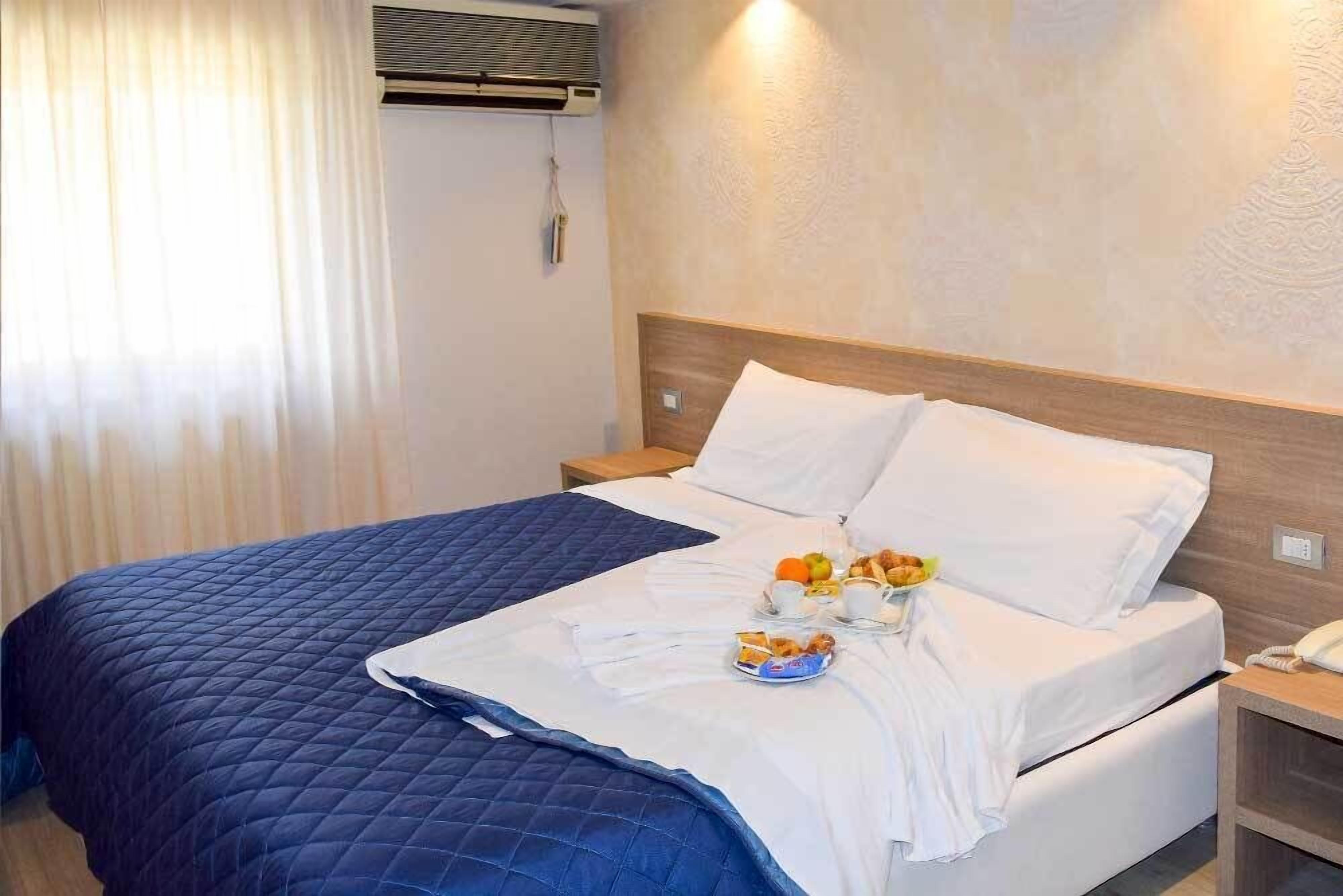 Ein Hotelzimmer mit Bett, Nachttisch und Wand-Klimaanlage.