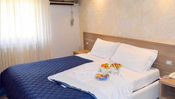 Ein Hotelzimmer mit Bett, Nachttisch und Wand-Klimaanlage.