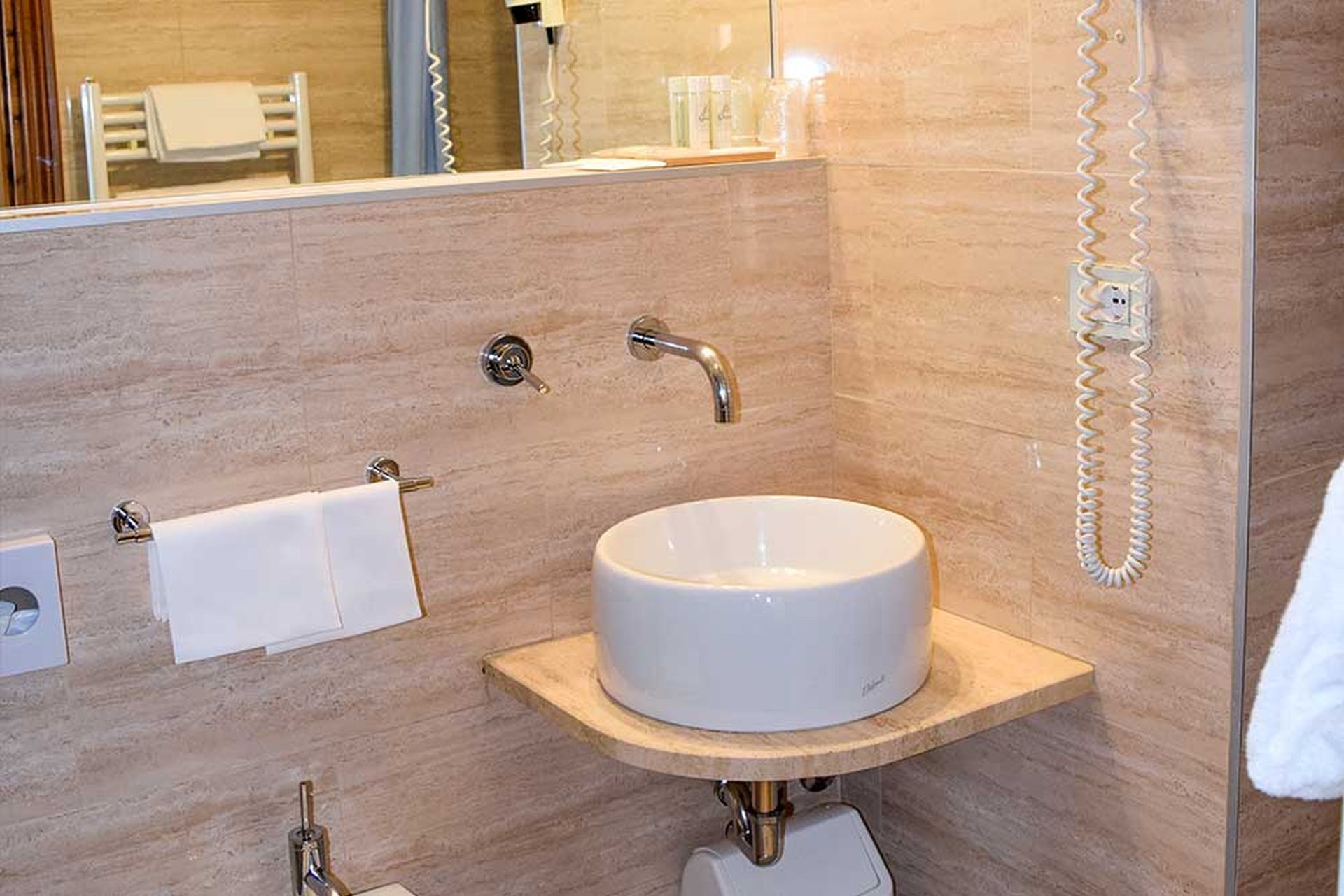 Une salle de bain avec un lavabo blanc, un porte-serviettes et un miroir.