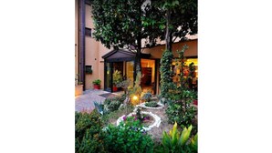 A hotel entrance with a garden pathway leading to the door. - Hotel Le Grazie (Assisi)