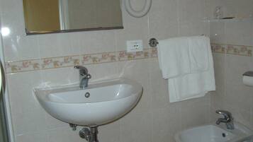 Un baño con lavamanos, bidé y un taburete pequeño.