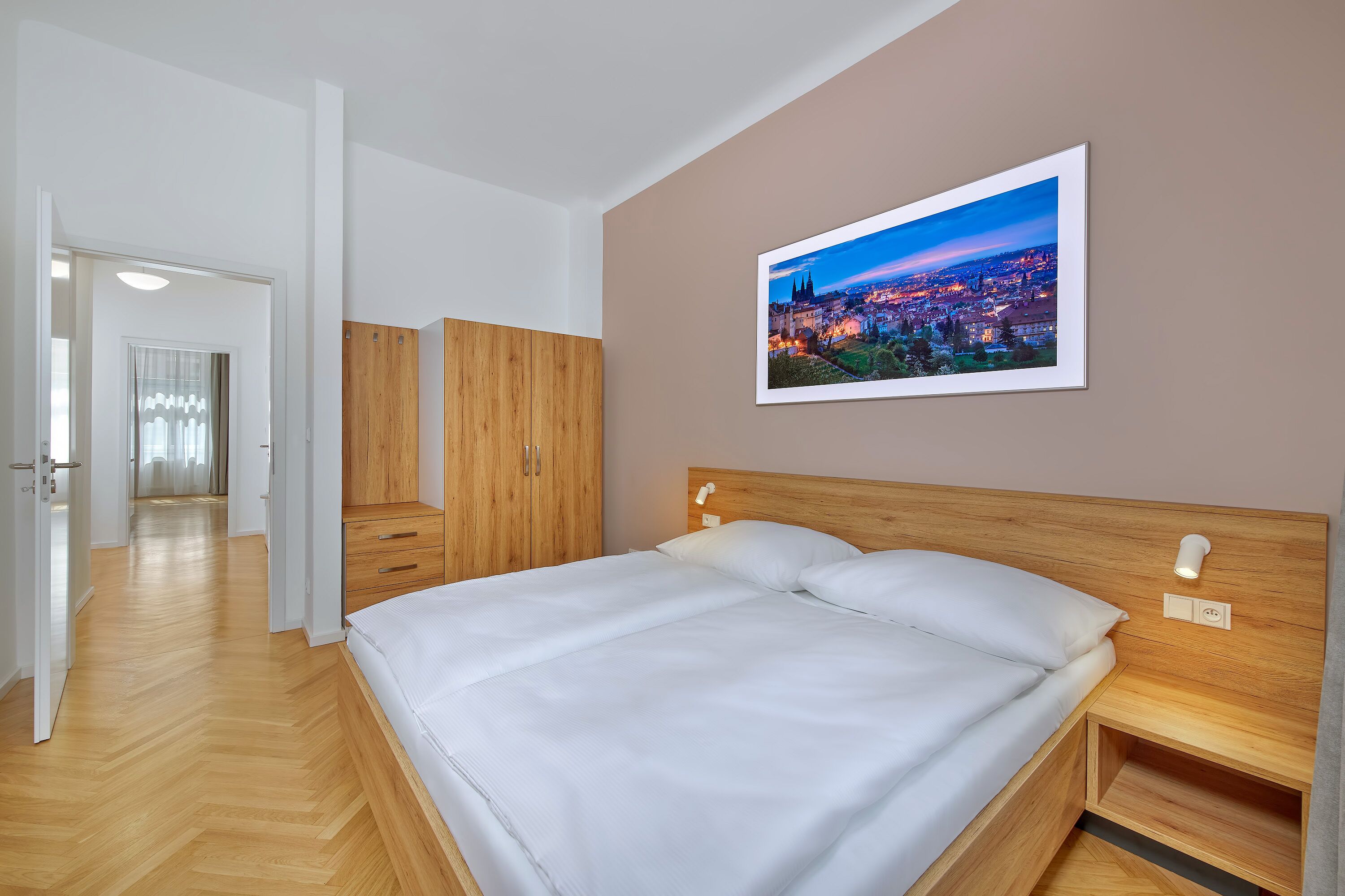 A bedroom with a large bed, wooden headboard, and a cityscape painting on the wall.