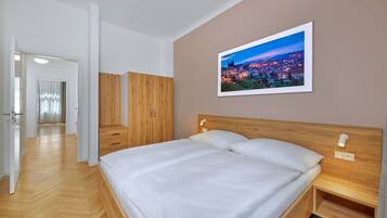 A bedroom with a large bed, wooden headboard, and a cityscape painting on the wall.