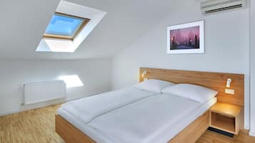 A modern bedroom with a skylight, a bed with wooden headboard, a nightstand, and a framed picture on the wall.