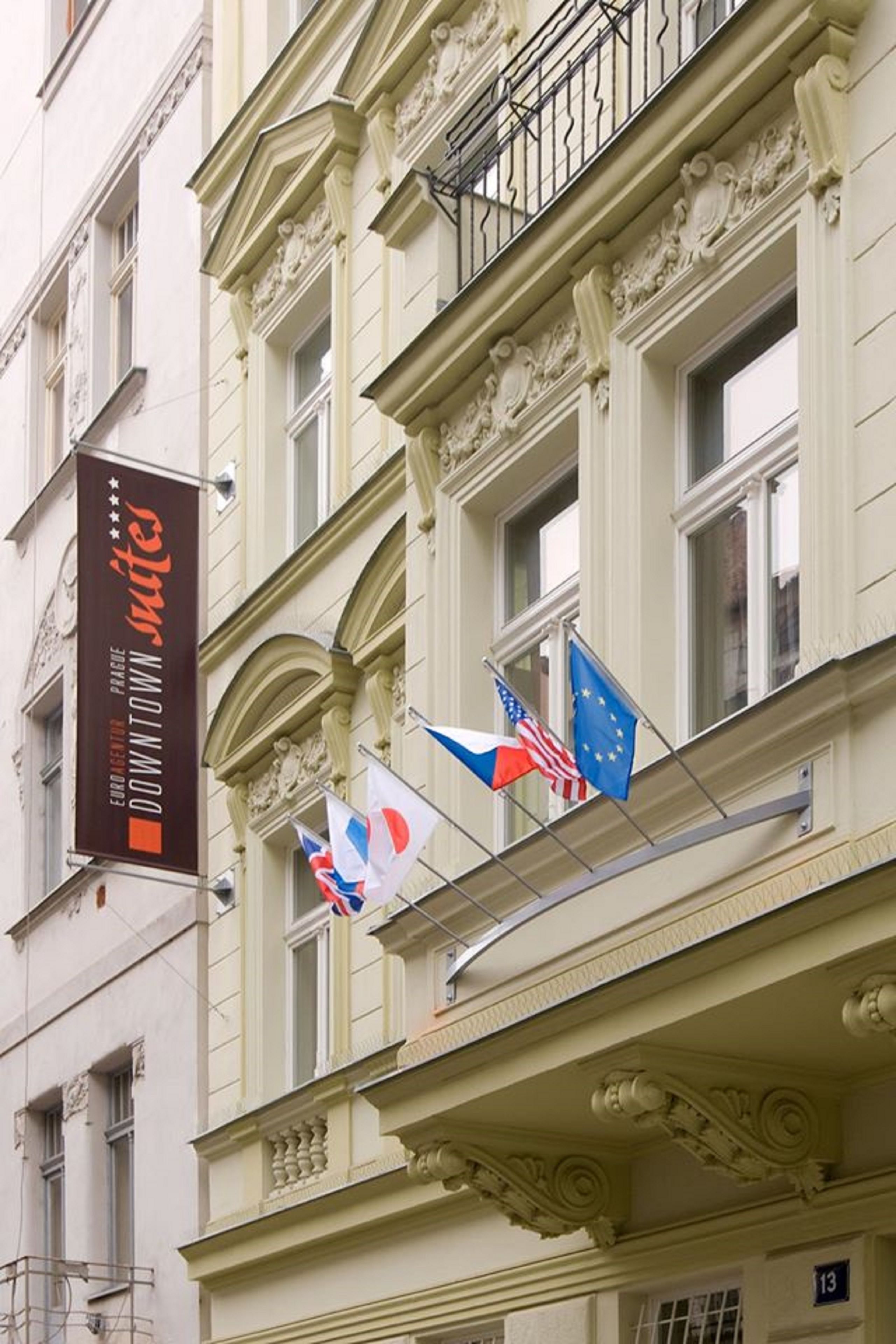 Ein Gebäude mit aufwendiger Architektur, einem Schild mit der Aufschrift 'Euro Downtown Suites' und mehreren Flaggen, darunter die amerikanische und die Flagge der Europäischen Union.