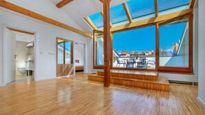 A spacious room with wooden floors, large skylights, and a view of the cityscape. - DownTown Suites Kodanská (Prague)
