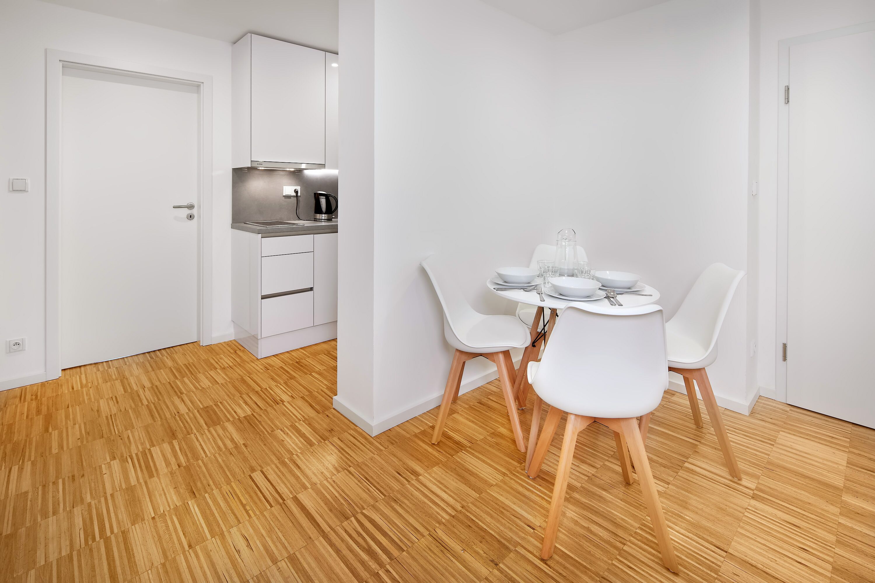 Cuina moderna amb armaris blancs i una campana extractora d'acer inoxidable.