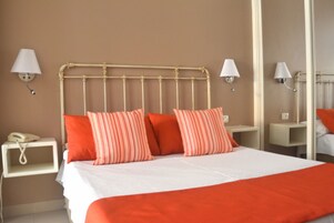 Habitación de hotel con cama, dos lámparas de noche, una mesita de noche y un espejo.