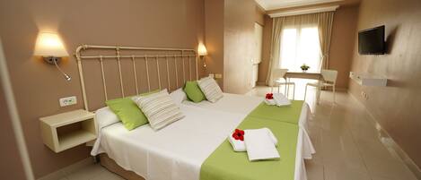 A hotel room with two beds, a desk, a chair, a TV, and a window with curtains.