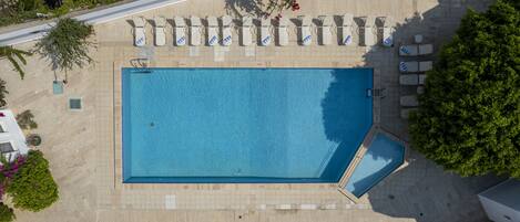 Vista aérea de una piscina rectangular con sillas de descanso y una piscina pequeña contigua.