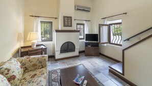 Una sala de estar con chimenea, un sofá, una mesa de centro, un televisor y una escalera.