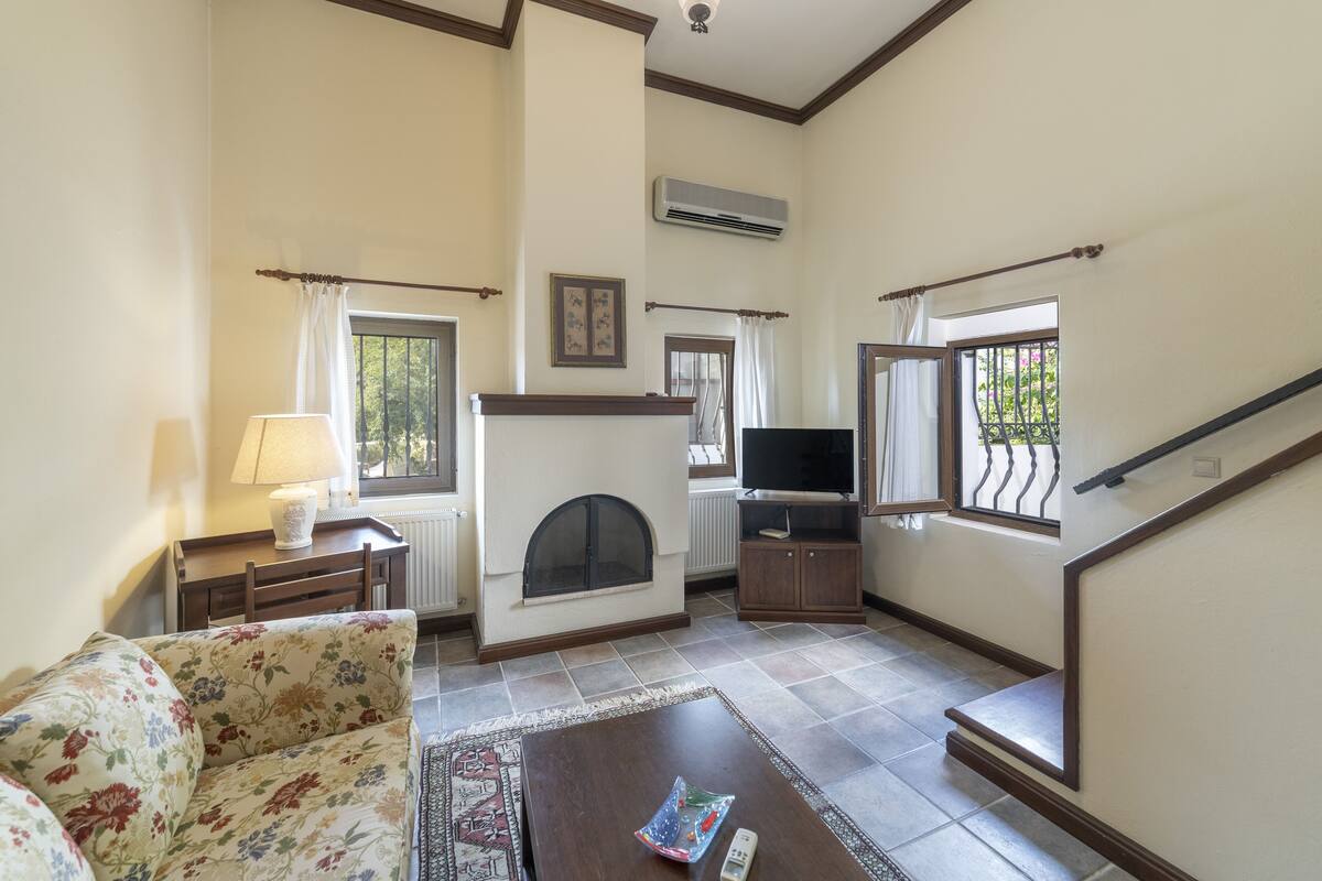 A living room with a fireplace, a sofa, a coffee table, a television, and a staircase.