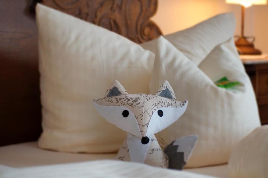 A bed with a decorative pillow featuring a fox design and a headboard.