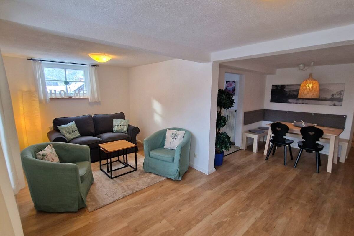A living room with a sofa, two armchairs, a coffee table, and a dining area with a table and chairs.