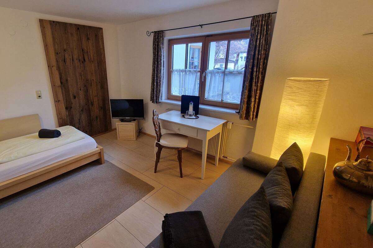 A compact room with a bed, a desk, a chair, and a sofa.