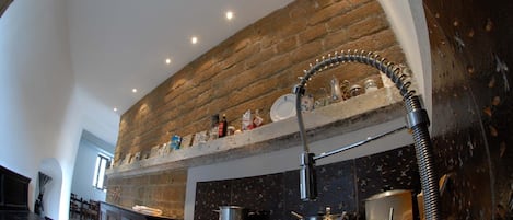 A kitchen with a stone backsplash, a stainless steel sink, and a gas stove.